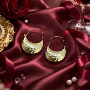 Woman wearing Luna Clutch hammered gold hoop earrings with luxury pouch-inspired Korean statement design