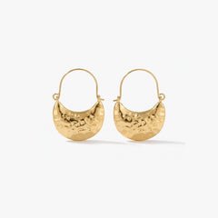 Woman wearing Luna Clutch hammered gold hoop earrings with luxury pouch-inspired Korean statement design
