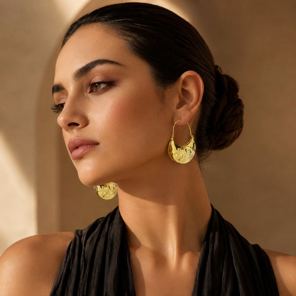 Woman wearing Luna Clutch hammered gold hoop earrings with luxury pouch-inspired Korean statement design