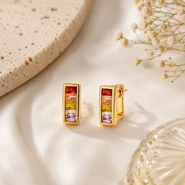 Woman wearing rainbow crystal gold huggie earrings with colorful prism stones and modern Korean luxury design