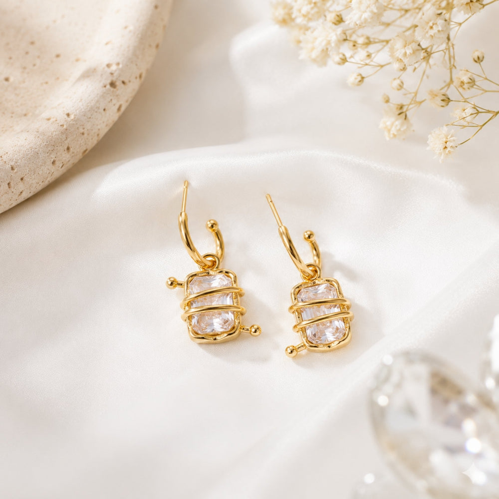 Woman wearing crystal wrapped gold hoop earrings with emerald-cut stones and modern Korean luxury design