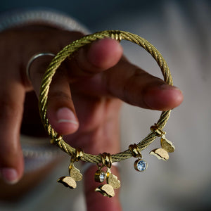 Gold butterfly charm bracelet for women by Sajna Sawarnaa featuring an elegant bangle design, perfect as a gift for her.