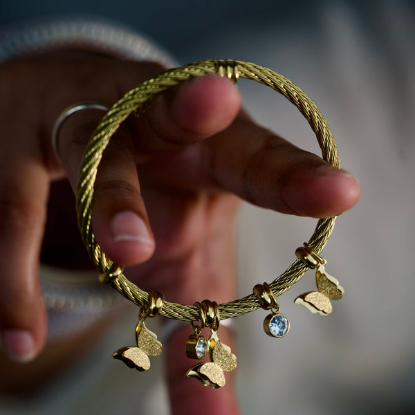 Gold butterfly charm bracelet for women by Sajna Sawarnaa featuring an elegant bangle design, perfect as a gift for her.