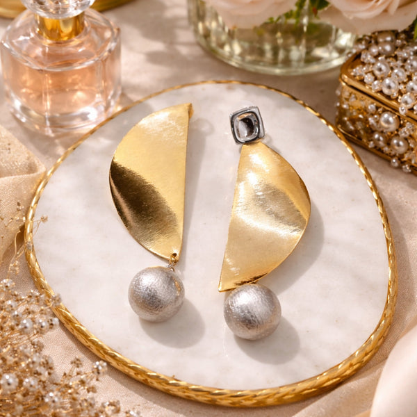 Luxury gold abstract statement earrings with textured silver pearl drops worn by a woman in elegant modern styling