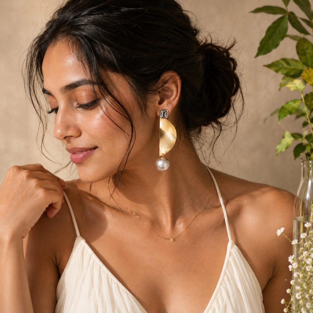 Luxury gold abstract statement earrings with textured silver pearl drops worn by a woman in elegant modern styling