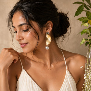Luxury gold abstract statement earrings with textured silver pearl drops worn by a woman in elegant modern styling