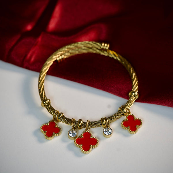 Red charm bracelet with gold finish featuring lucky clover charms by Sajna Sawarnaa. Stylish jewelry accessory.