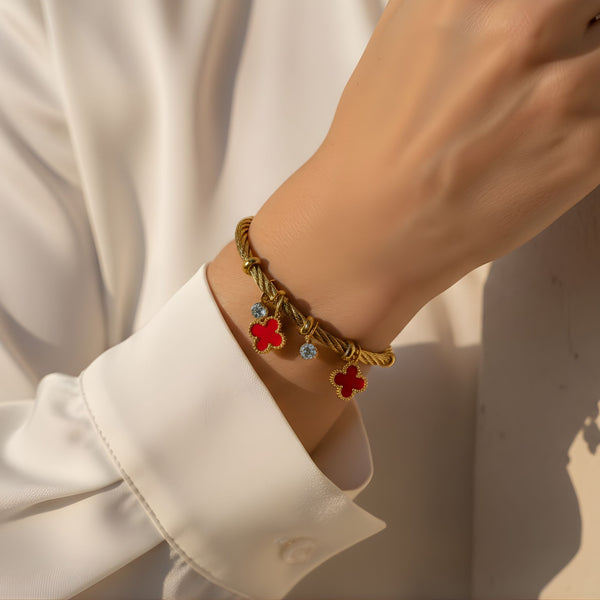 Red charm bracelet with gold finish featuring lucky clover charms by Sajna Sawarnaa, stylish jewelry accessory.