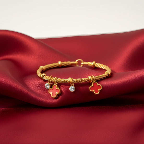 Red charm bracelet with gold finish featuring lucky clover charms by Sajna Sawarnaa, stylish jewelry accessory.