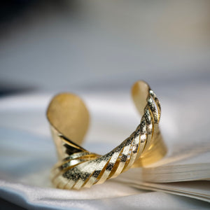 Twisted gold cuff bracelet for women featuring textured luxury design and anti-tarnish finish by Sajna Sawarnaa.