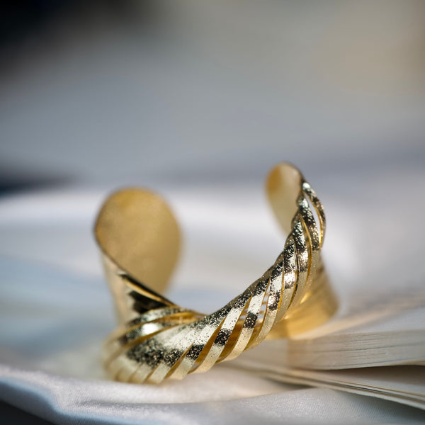Twisted gold cuff bracelet for women featuring textured luxury design and anti-tarnish finish by Sajna Sawarnaa.