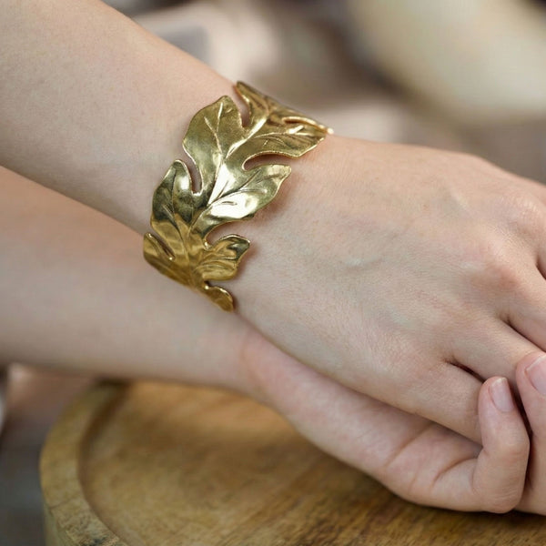Gold women's bracelet with a leaf pattern and open cuff design, featuring nature-inspired jewelry by Sajna Sawarnaa.