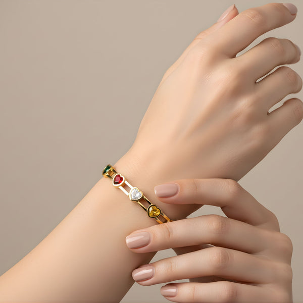 Elegant women's gold bracelet with multicolor heart-shaped gemstone charms, featuring a luxurious design by Sajna Sawarnaa.