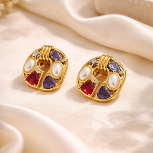 18K gold plated vintage statement earrings with faux pearls and colorful geometric gemstones resting on luxurious white silk fabric.