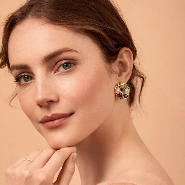 Beautiful female model looking at the camera wearing vintage multi-stone and pearl gold statement earrings.