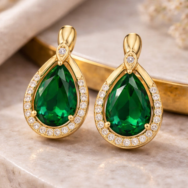 Gold-tone emerald drop earrings by SAJNA SAWARNAA featuring pear-shaped halo design and anti-tarnish finish for women.