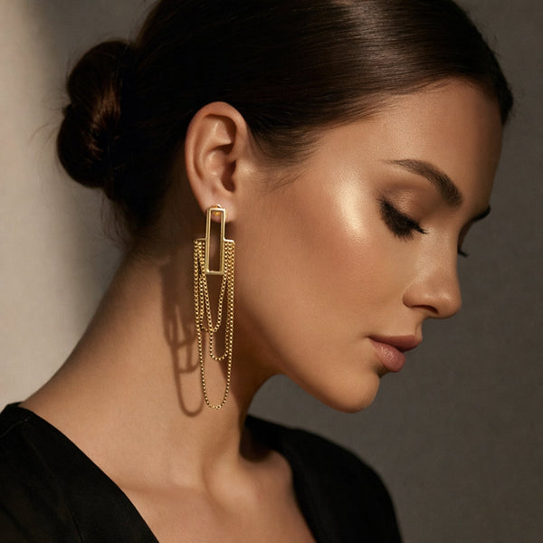 Model wearing gold cascade chain drop earrings with rectangle bar stud – elegant on-ear side profile shot