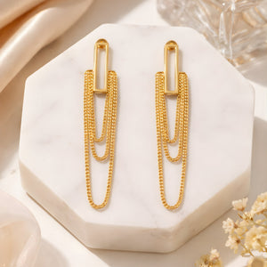 Long gold chain tassel drop earrings on white marble hexagon tray – lifestyle product shot
