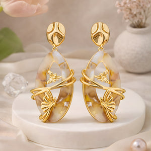     Elegant butterfly marble statement earrings displayed on beige luxury podium with soft aesthetic background