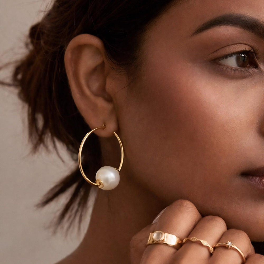 Gold hoop earrings with pearl beads on a white background