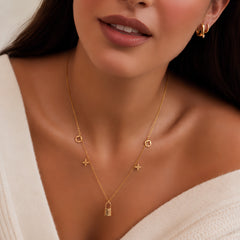 Gold clover and lock charm necklace worn by a model