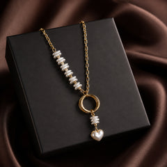 Gold-tone pearl-look heart drop necklace styled on a dark editorial background