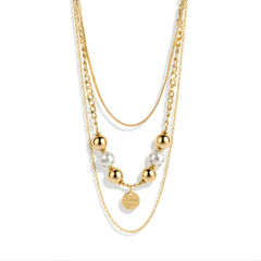 Layered gold-tone bead and message charm necklace close-up on a white background
