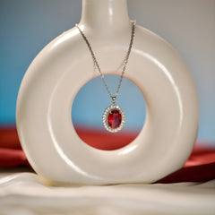 Silver-tone red stone-accent oval pendant necklace styled on an editorial background