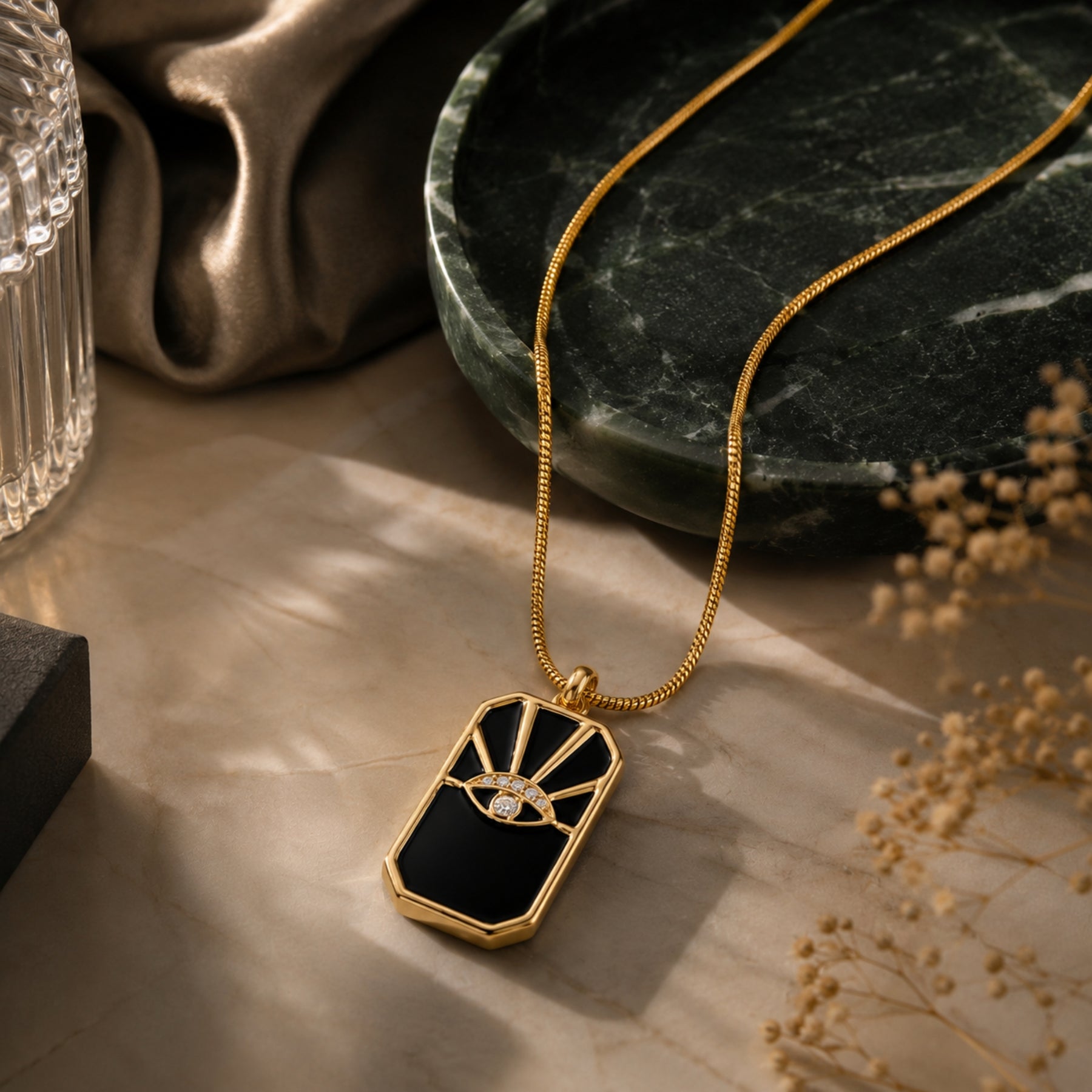 Black evil eye pendant necklace with gold-tone chain styled on marble