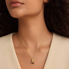 Woman wearing a gold-tone sunburst pendant necklace