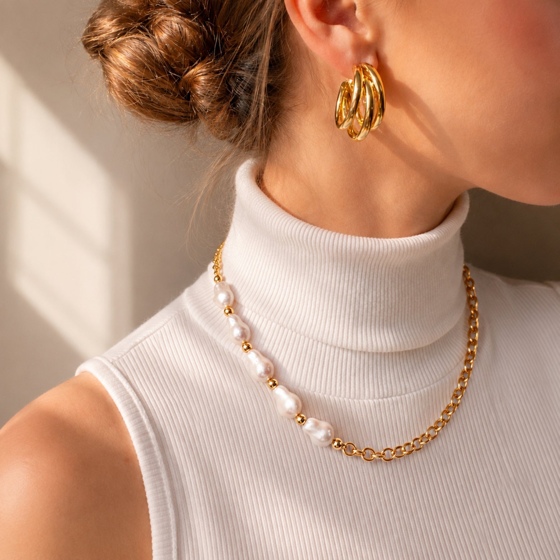 Woman wearing a gold-tone chain necklace with irregular pearl accents