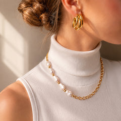 Woman wearing a gold-tone chain necklace with irregular pearl accents
