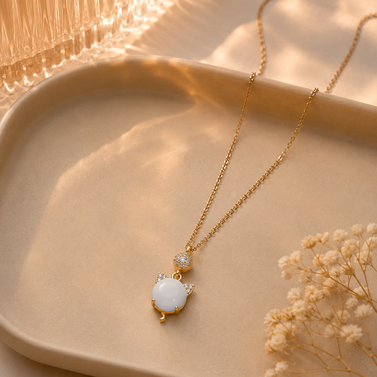 Gold-tone white cat charm pendant necklace styled on a warm editorial background