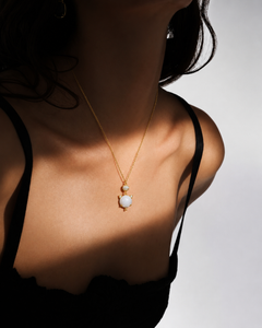 Woman wearing a gold-tone white cat charm pendant necklace