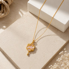 Gold-tone pink floral charm pendant necklace styled on a neutral editorial background